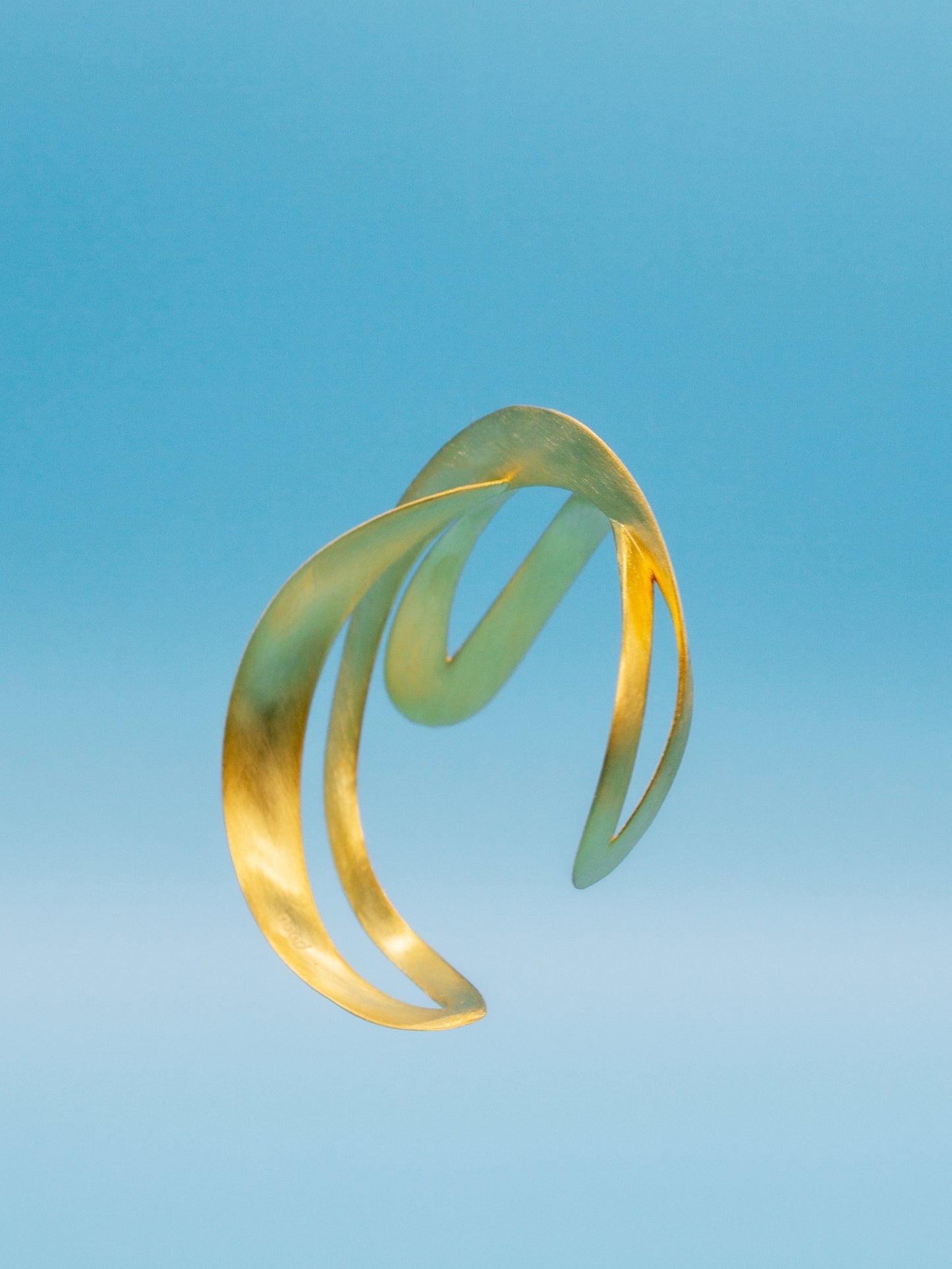 3D printed futuristic gold bracelet on a blue gradient background