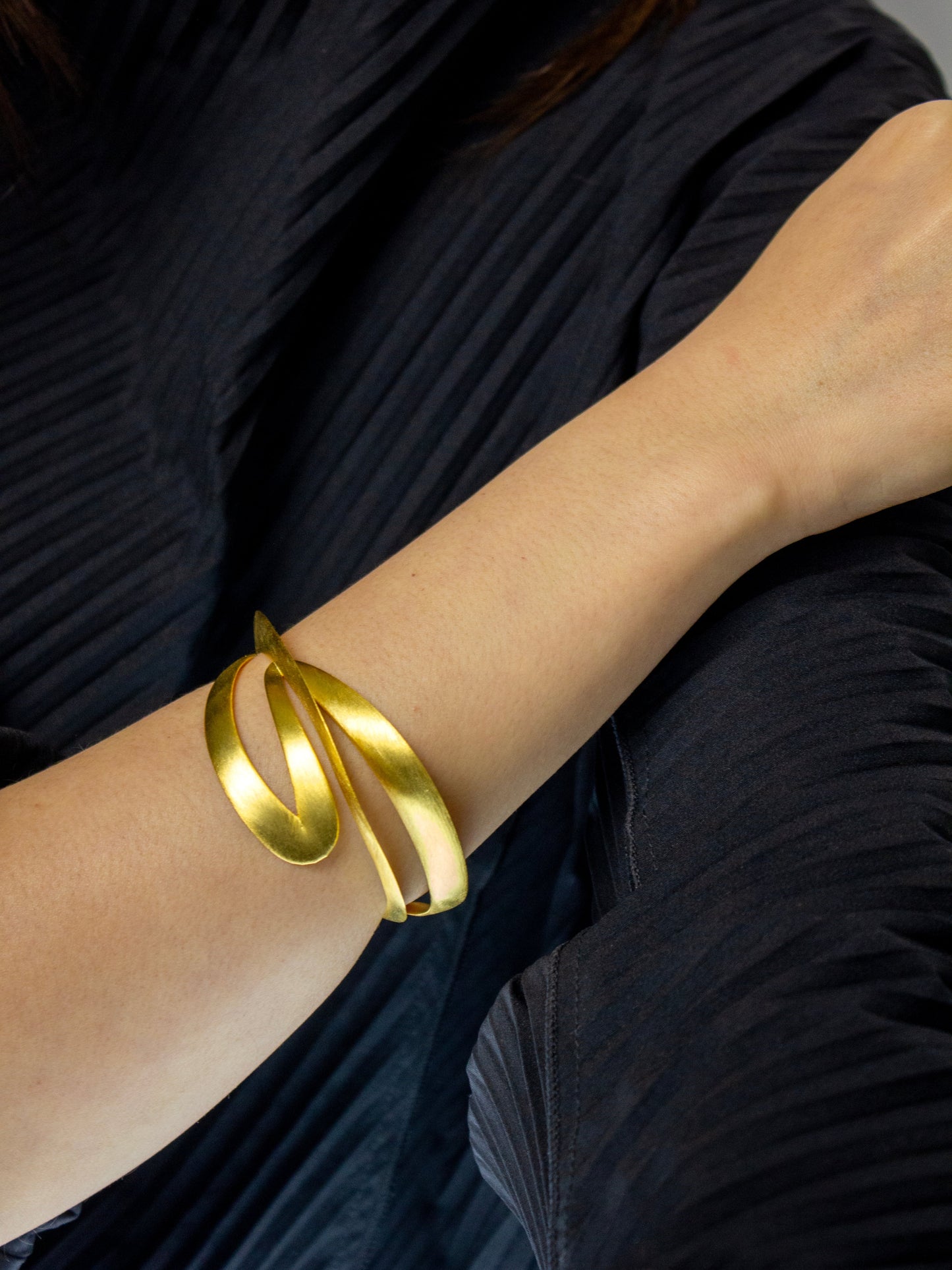 Gold bracelet on a person's wrist with a dark background