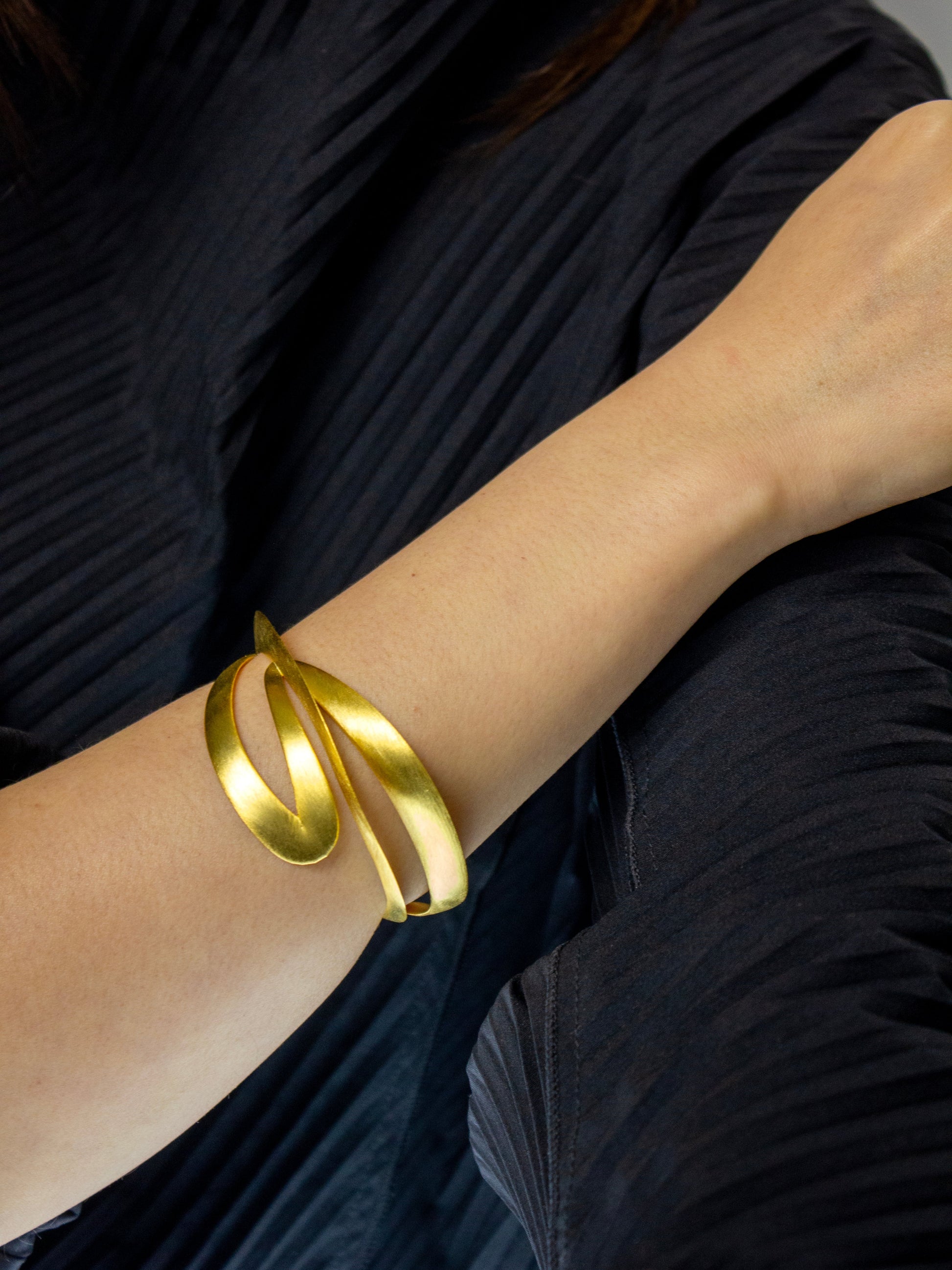 Gold bracelet on a person's wrist with a dark background