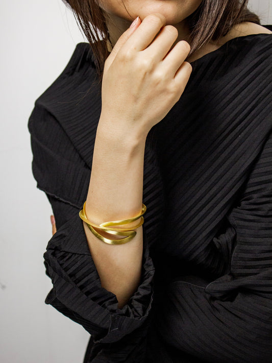 Person wearing a gold bracelet on a plain background
