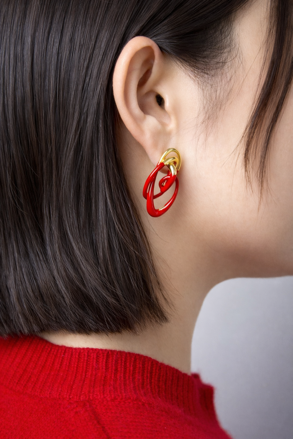 Independent designer statement earrings in glossy red and gold, abstract sculptural drop earrings shown both worn on ear and as a product flat lay.