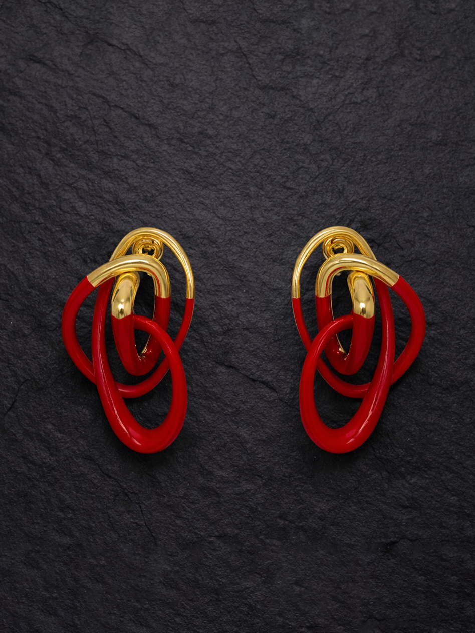 Glossy red and gold sculptural statement earrings by an independent designer, shown worn on ear and as a flat lay.