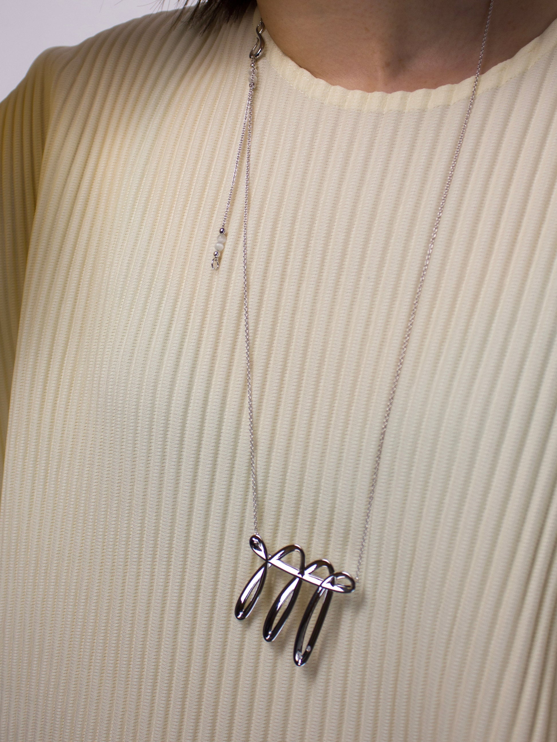 Close-up of nood Lucky Stroke Necklace worn over knitwear, highlighting its flowing sculptural form, turquoise details, and custom clasp