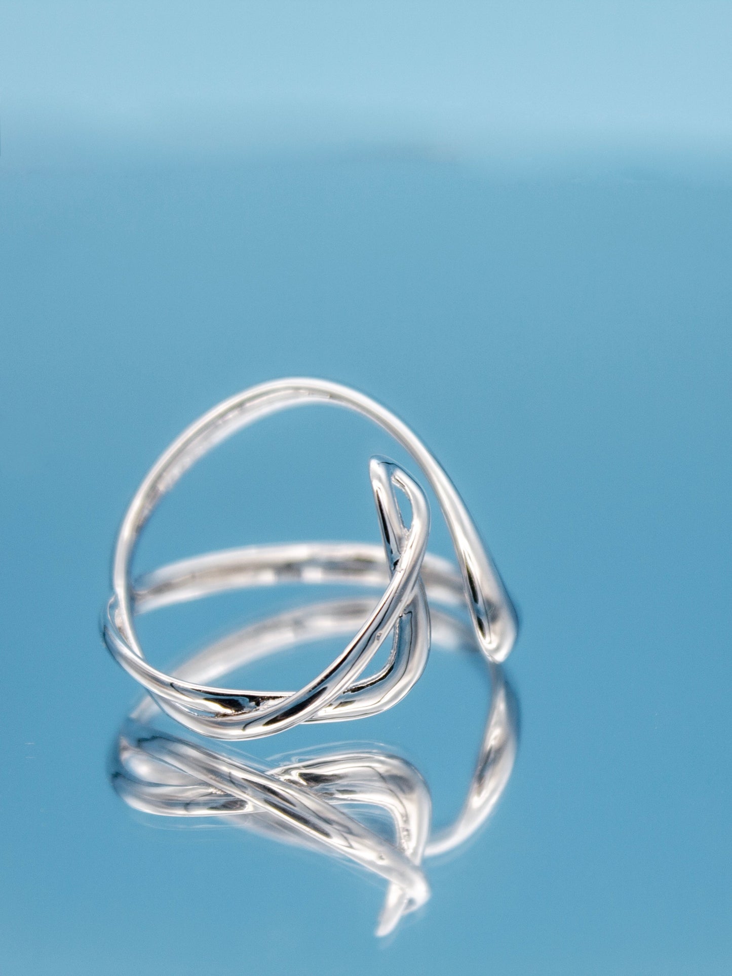 sculptural silver ring with a fluid, curved open-band design